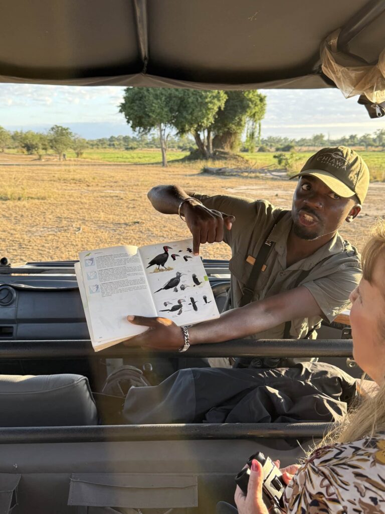 A guide showing a family birds in a book on a African safari.